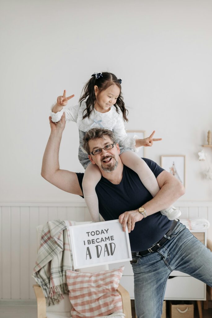 A joyful moment of a father and daughter celebrating in a cozy room with a sign reading 'Today I Became a Dad'.